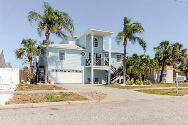 coastal inspired home featuring stairway, an attached garage, driveway, and fence