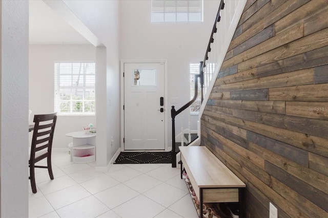 tiled entrance foyer featuring stairs and baseboards