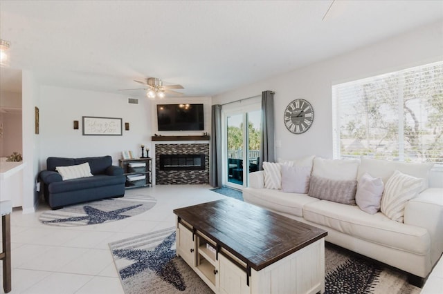 living room featuring light tile patterned floors, visible vents, a fireplace, and a ceiling fan