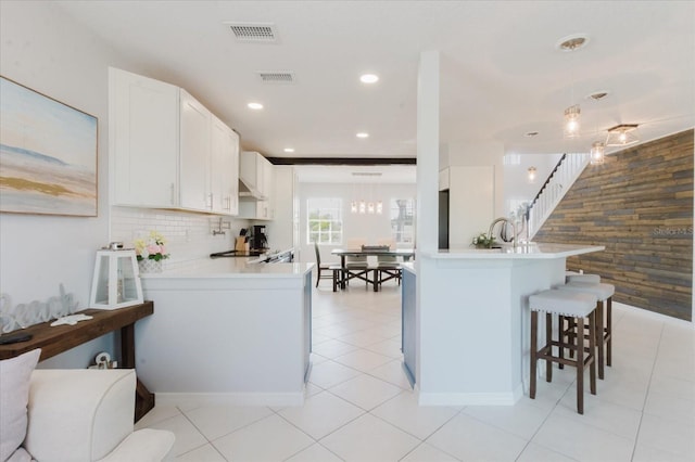 kitchen featuring visible vents, a peninsula, and decorative backsplash