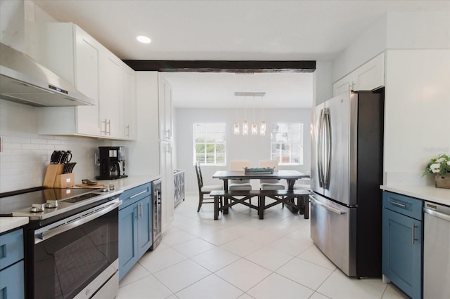 kitchen featuring under cabinet range hood, decorative backsplash, blue cabinetry, and appliances with stainless steel finishes