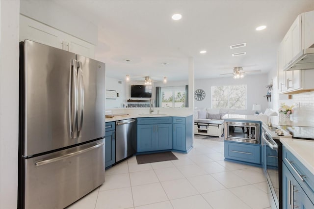 kitchen featuring a ceiling fan, a sink, open floor plan, a peninsula, and appliances with stainless steel finishes