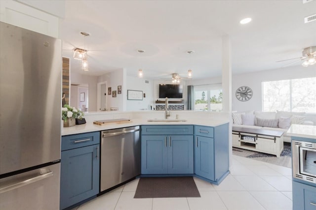 kitchen with open floor plan, appliances with stainless steel finishes, light countertops, and a ceiling fan