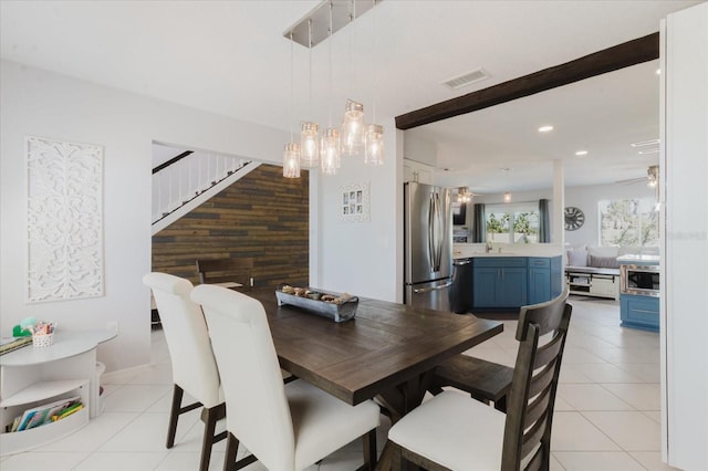 dining room with visible vents, wooden walls, stairs, light tile patterned floors, and ceiling fan with notable chandelier