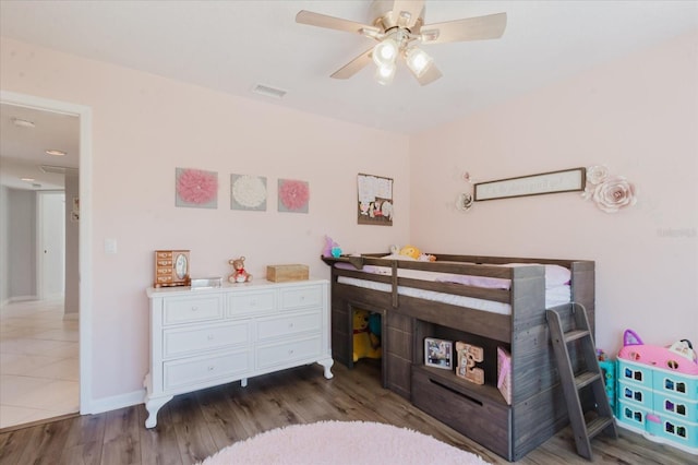 bedroom featuring visible vents, baseboards, wood finished floors, and a ceiling fan