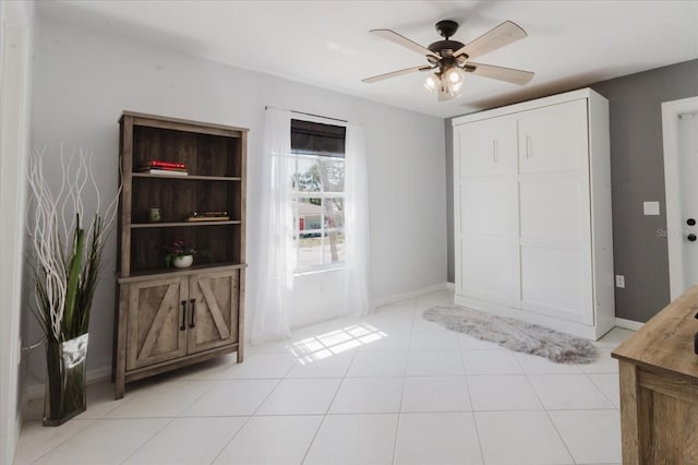 interior space featuring light tile patterned floors, baseboards, and ceiling fan