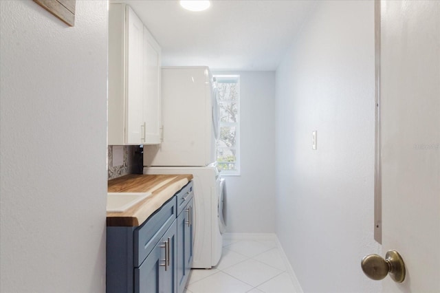 laundry room with baseboards, cabinet space, a healthy amount of sunlight, and light tile patterned flooring