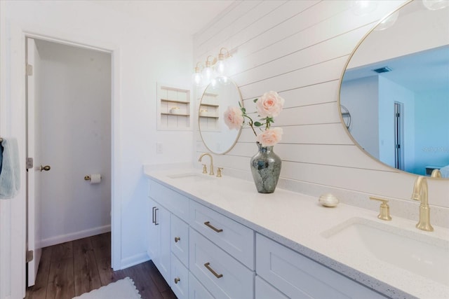 full bathroom featuring double vanity, wood finished floors, visible vents, and a sink