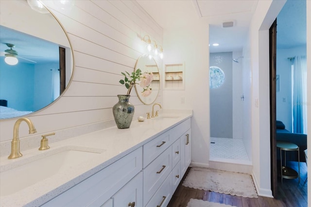 bathroom featuring a sink, wood finished floors, double vanity, and a walk in shower