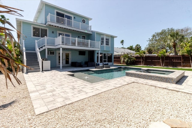 rear view of house featuring fence, french doors, a balcony, an in ground hot tub, and a patio area