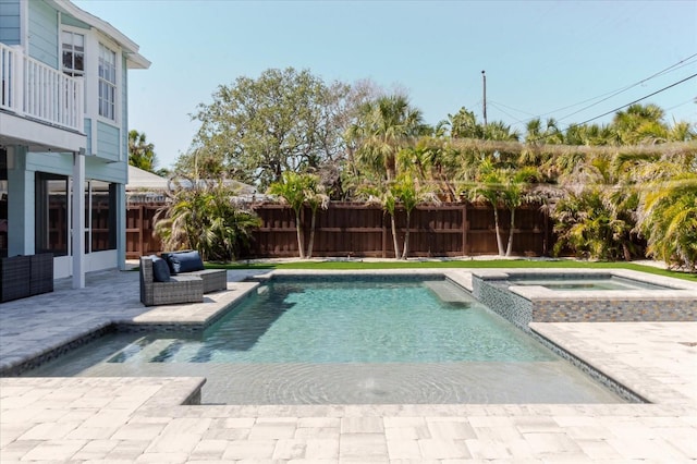 view of pool featuring a patio area, a pool with connected hot tub, and a fenced backyard