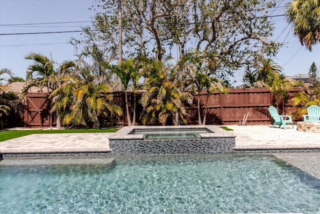 outdoor pool with an in ground hot tub, a fenced backyard, and a patio area