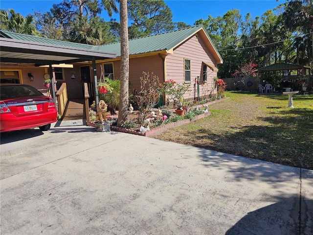 view of side of home with metal roof, driveway, a lawn, and a carport