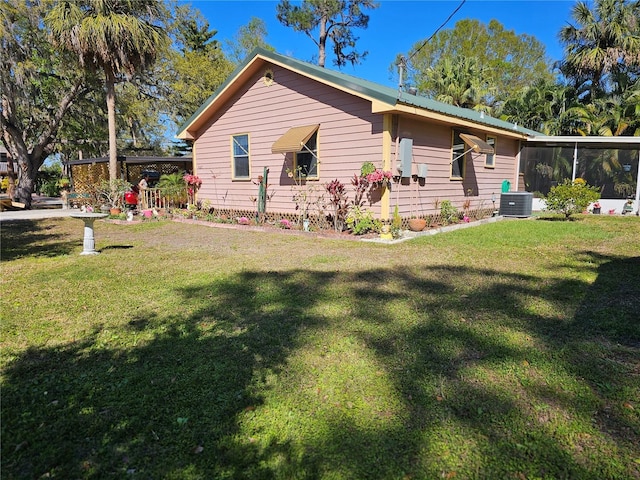 view of home's exterior with central AC, a yard, and a sunroom