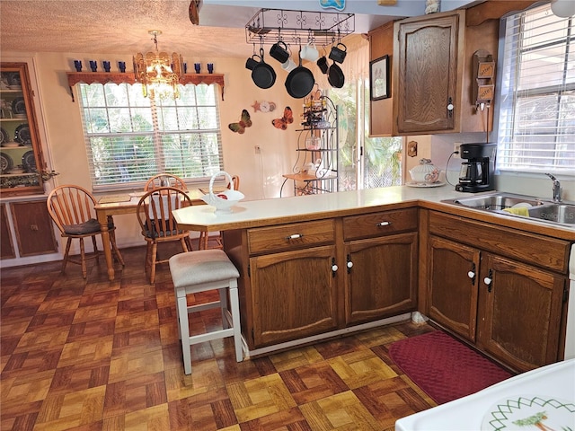 kitchen featuring a peninsula, a healthy amount of sunlight, light countertops, and a sink