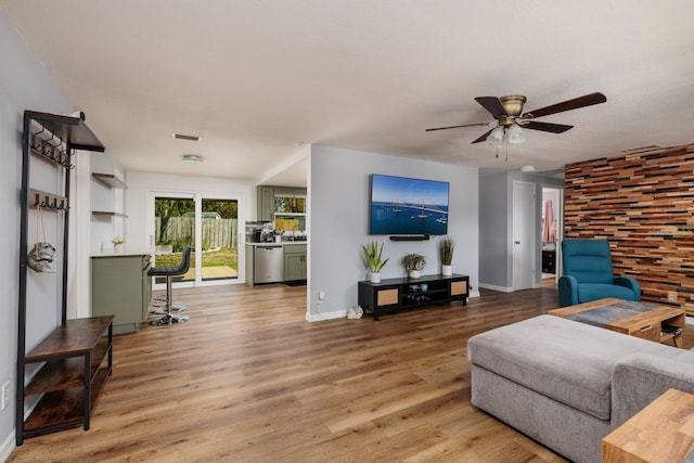 living room featuring visible vents, baseboards, light wood-style floors, and a ceiling fan