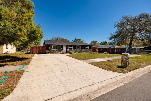 single story home with driveway, a front yard, and fence