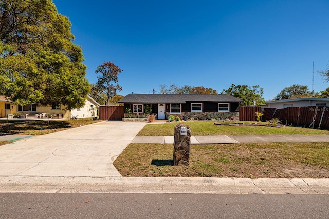 single story home featuring a front lawn, concrete driveway, and fence