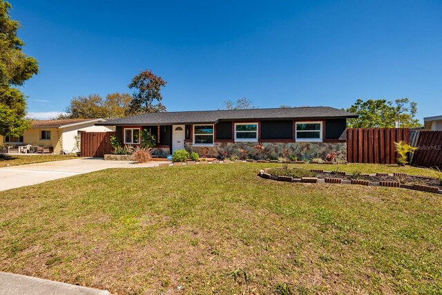 ranch-style home featuring stone siding, concrete driveway, a front lawn, and fence