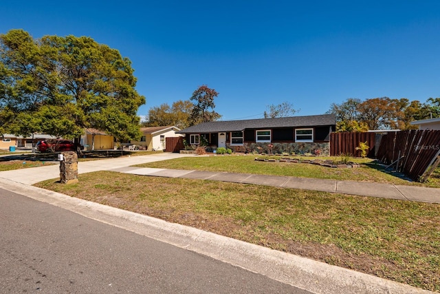 ranch-style home with stone siding, a front yard, driveway, and fence