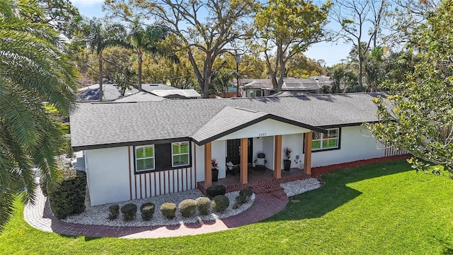 view of front of property featuring stucco siding, a shingled roof, and a front yard