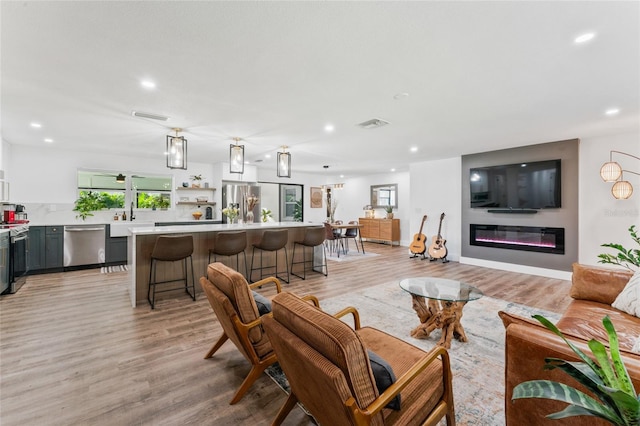 living room with a glass covered fireplace, recessed lighting, and light wood-type flooring