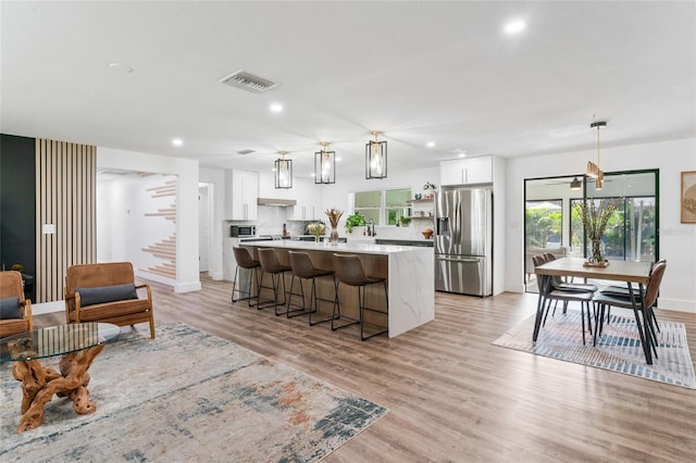 kitchen featuring visible vents, light wood-style flooring, a center island, appliances with stainless steel finishes, and white cabinets