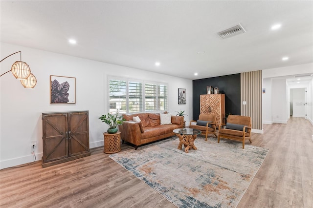 living area with recessed lighting, wood finished floors, visible vents, and baseboards