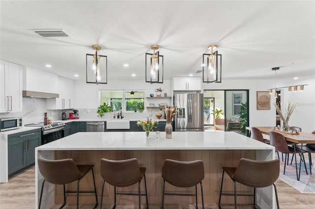 kitchen featuring decorative backsplash, appliances with stainless steel finishes, light wood-style floors, and a sink