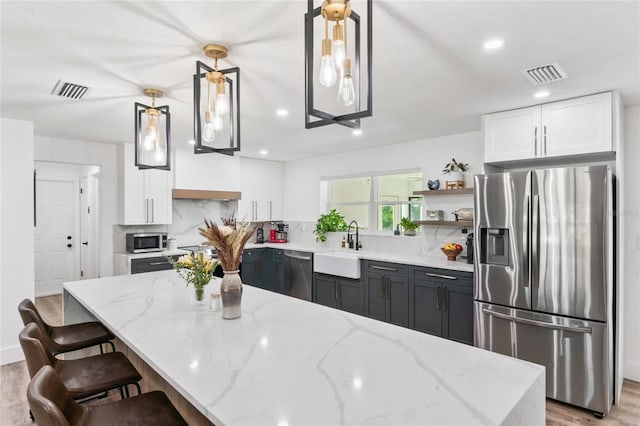 kitchen with white cabinetry, a sink, visible vents, and stainless steel appliances