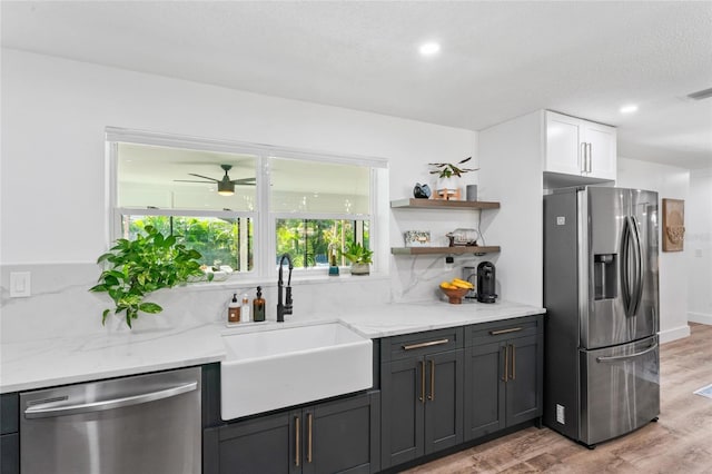 kitchen featuring light wood finished floors, white cabinets, stainless steel appliances, and a sink