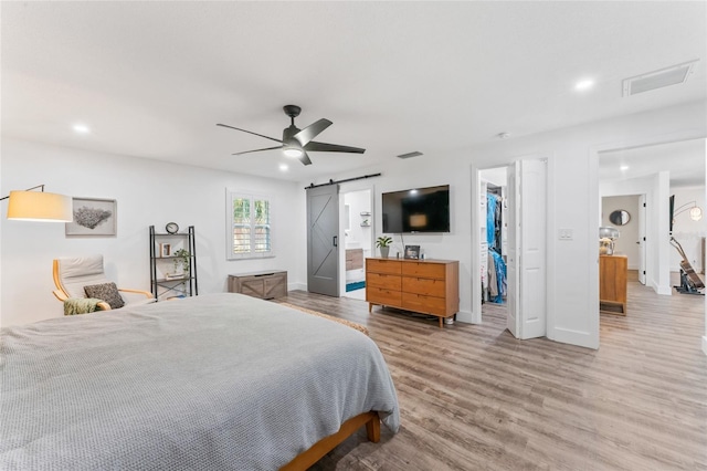 bedroom featuring baseboards, visible vents, recessed lighting, a barn door, and light wood-type flooring