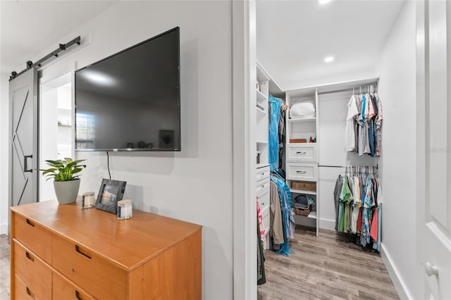 spacious closet with a barn door and light wood finished floors