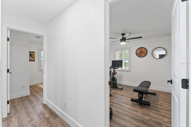 exercise area with visible vents, wood finished floors, baseboards, and ceiling fan