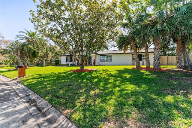 ranch-style house with stucco siding, a front lawn, and fence