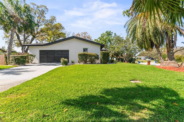 exterior space featuring stucco siding, a lawn, a garage, and driveway