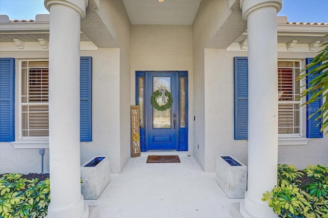 view of exterior entry with a tile roof and stucco siding