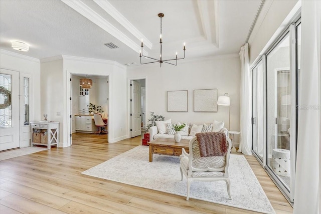 living room featuring light wood finished floors, a chandelier, crown molding, and a raised ceiling