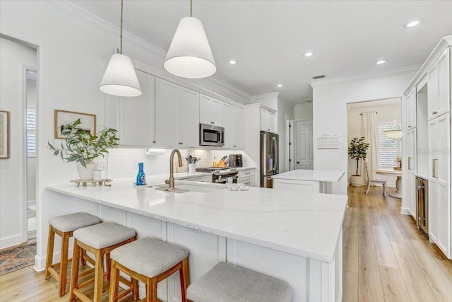 kitchen with a sink, a kitchen island, backsplash, stainless steel appliances, and a peninsula