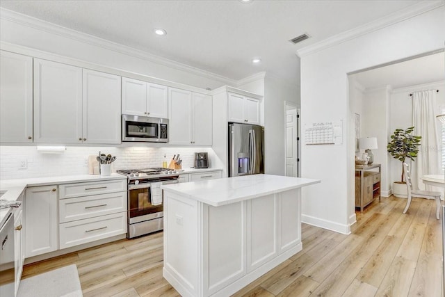 kitchen with visible vents, a kitchen island, stainless steel appliances, decorative backsplash, and light wood-style floors