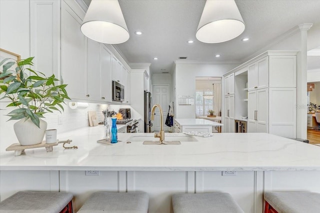 kitchen with a sink, tasteful backsplash, appliances with stainless steel finishes, a peninsula, and crown molding