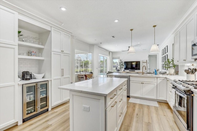 kitchen featuring light wood finished floors, stainless steel appliances, wine cooler, and light countertops