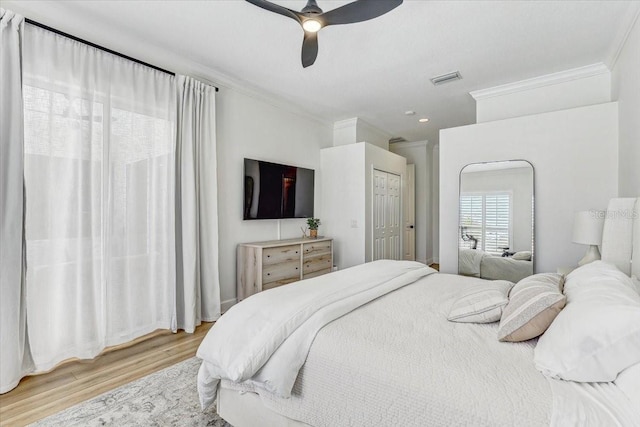 bedroom with visible vents, ceiling fan, ornamental molding, light wood-style flooring, and a closet