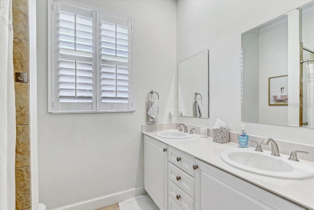 full bath featuring double vanity, baseboards, and a sink