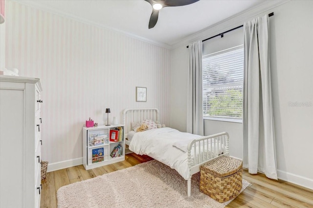 bedroom featuring hardwood / wood-style floors, a ceiling fan, baseboards, wallpapered walls, and ornamental molding