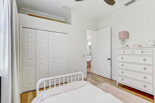 bedroom with visible vents, crown molding, ceiling fan, light wood-type flooring, and a closet