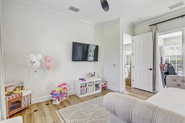 bedroom with crown molding, wood finished floors, visible vents, and baseboards