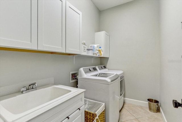 laundry room featuring a sink, baseboards, light tile patterned floors, cabinet space, and separate washer and dryer