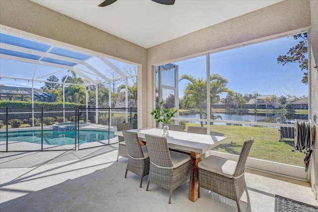 sunroom featuring a ceiling fan and a water view