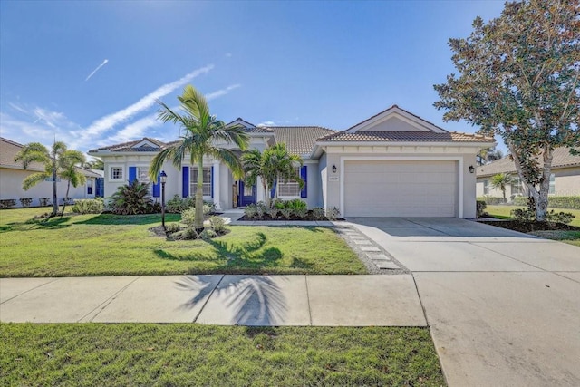 view of front of property with a tiled roof, a front yard, stucco siding, a garage, and driveway